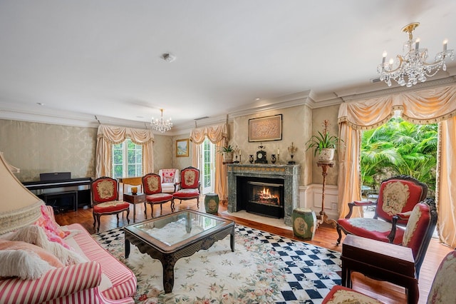 living area with ornamental molding, wood finished floors, and a notable chandelier