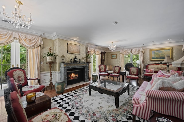 living room featuring a wainscoted wall, a premium fireplace, ornamental molding, an inviting chandelier, and wood finished floors