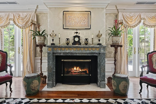 sitting room featuring a fireplace, visible vents, crown molding, and wood finished floors