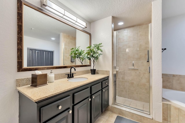 full bath with a stall shower, tile patterned floors, a textured ceiling, vanity, and a bath