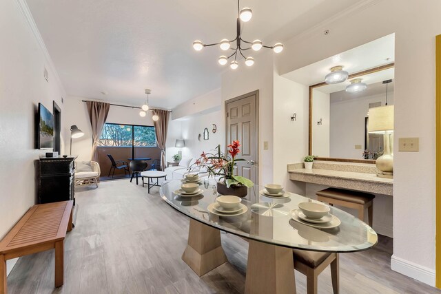 dining space featuring crown molding, light wood-type flooring, and an inviting chandelier