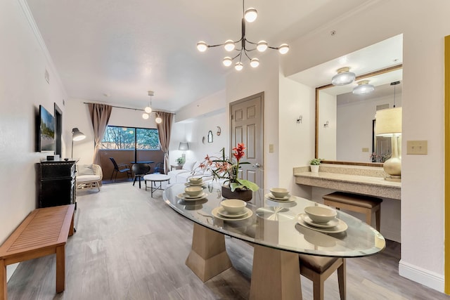 dining area with ornamental molding, a notable chandelier, and wood finished floors