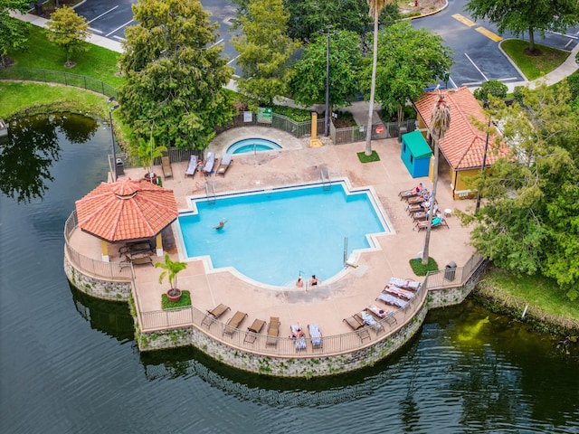 view of swimming pool featuring a water view, fence, a community hot tub, and a patio