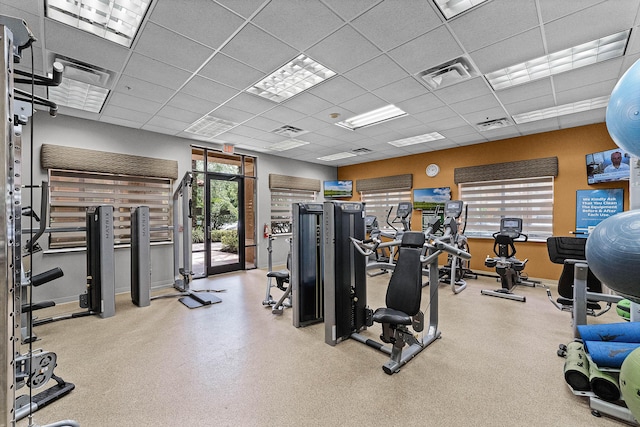 exercise room with baseboards, visible vents, and a drop ceiling