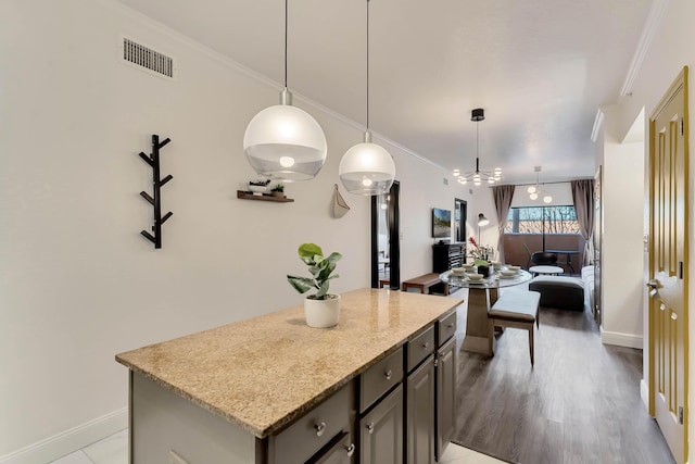 kitchen featuring crown molding, a center island, visible vents, and hanging light fixtures