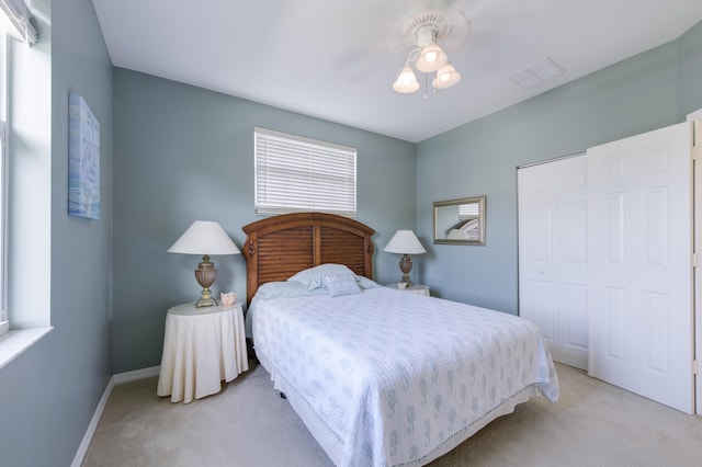 bedroom featuring a ceiling fan, baseboards, a closet, and light colored carpet