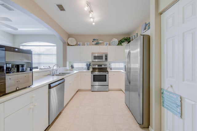 kitchen featuring sink, rail lighting, light tile patterned floors, stainless steel appliances, and white cabinets