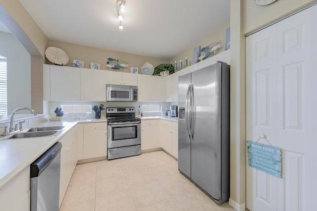 kitchen featuring light tile patterned floors, rail lighting, stainless steel appliances, and sink