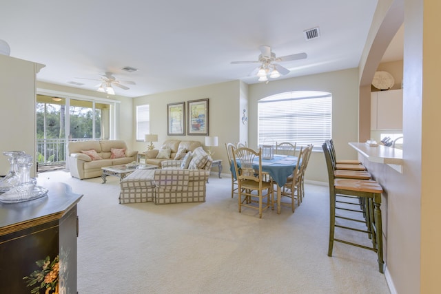 living area with light carpet, ceiling fan, and visible vents
