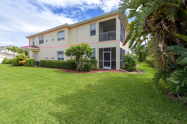 back of property featuring a balcony, cooling unit, and a yard