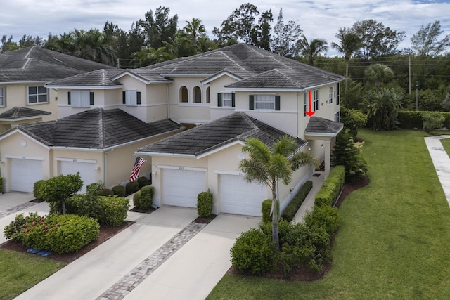 view of property featuring a tile roof, a front lawn, concrete driveway, and stucco siding
