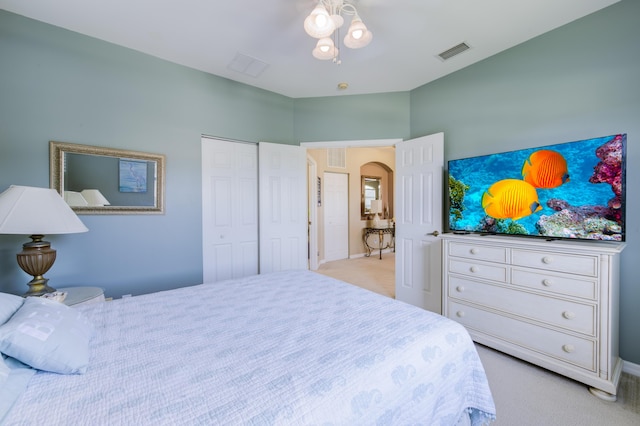 bedroom featuring arched walkways, a closet, visible vents, and light colored carpet