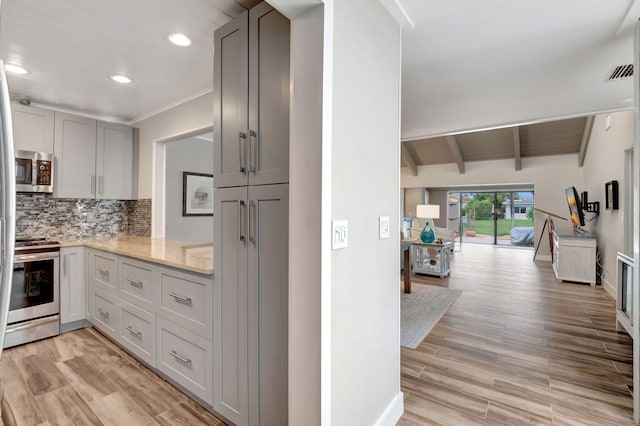 kitchen with light hardwood / wood-style floors, backsplash, vaulted ceiling with beams, and stainless steel appliances