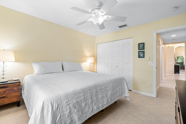 tiled bedroom with ceiling fan and a closet