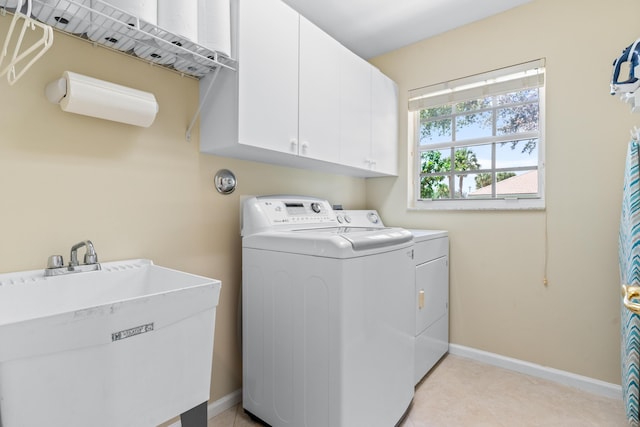 clothes washing area with separate washer and dryer, sink, and cabinets