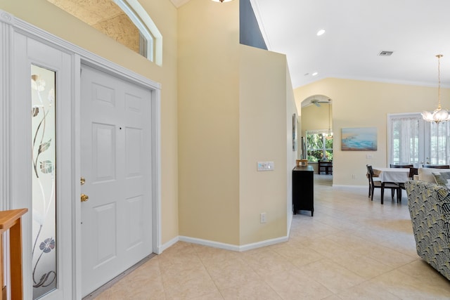 foyer entrance with vaulted ceiling, a chandelier, and light tile patterned flooring