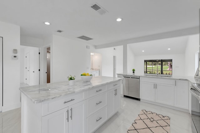 kitchen featuring white cabinetry, light stone countertops, a kitchen island, stainless steel dishwasher, and light tile flooring