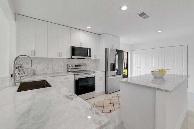 kitchen featuring light stone countertops, sink, white cabinetry, and appliances with stainless steel finishes