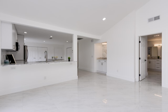 unfurnished living room featuring vaulted ceiling, sink, and light tile floors