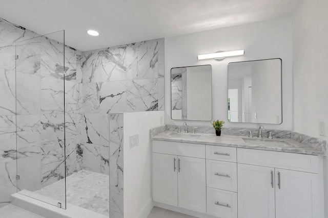 bathroom with a tile shower and double sink vanity