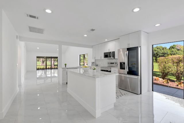 kitchen with white cabinetry, light stone countertops, appliances with stainless steel finishes, tasteful backsplash, and light tile floors