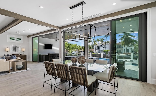 dining space with beam ceiling, light hardwood / wood-style flooring, and ceiling fan with notable chandelier