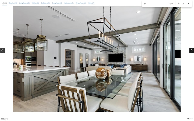 dining space featuring beamed ceiling, a stone fireplace, and light hardwood / wood-style flooring