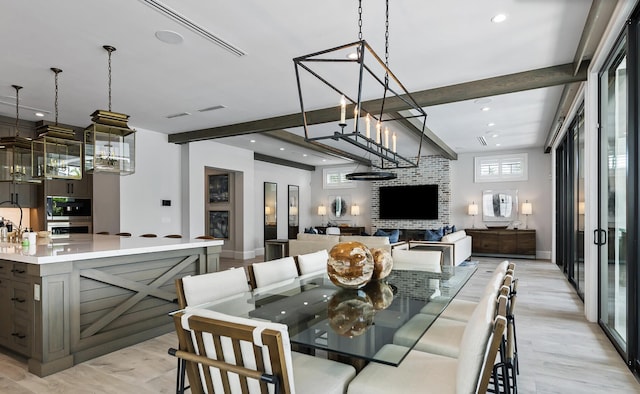 dining room with a large fireplace, plenty of natural light, beamed ceiling, and light hardwood / wood-style floors