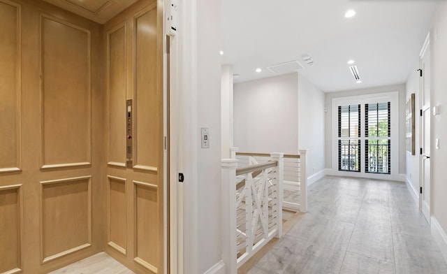 hallway featuring light wood-type flooring and elevator