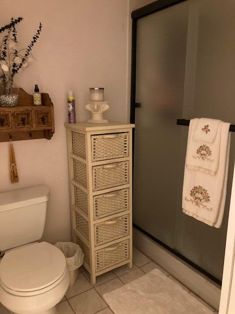 bathroom featuring tile patterned floors, an enclosed shower, and toilet