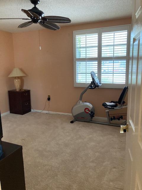 exercise area with carpet, a textured ceiling, and ceiling fan