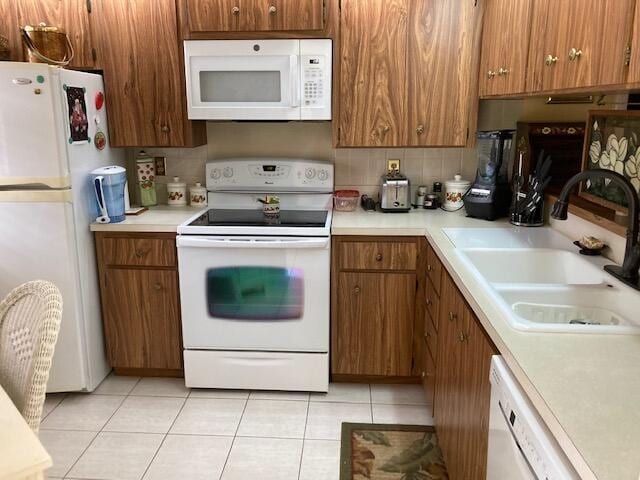 kitchen with backsplash, white appliances, sink, and light tile patterned floors