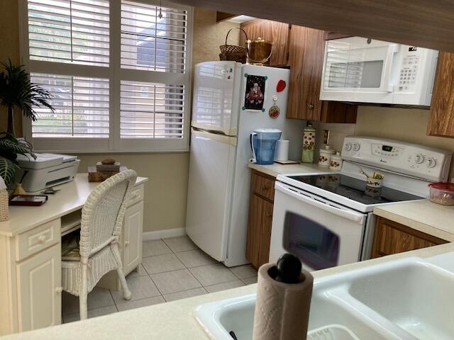 kitchen featuring sink, light tile patterned floors, and white appliances