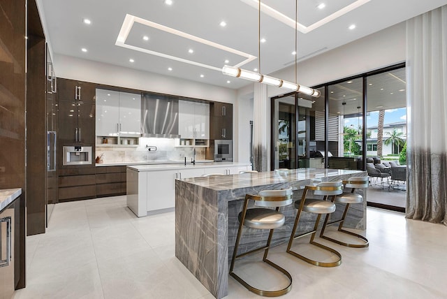 kitchen featuring dark brown cabinetry, a kitchen island with sink, white cabinets, ventilation hood, and modern cabinets