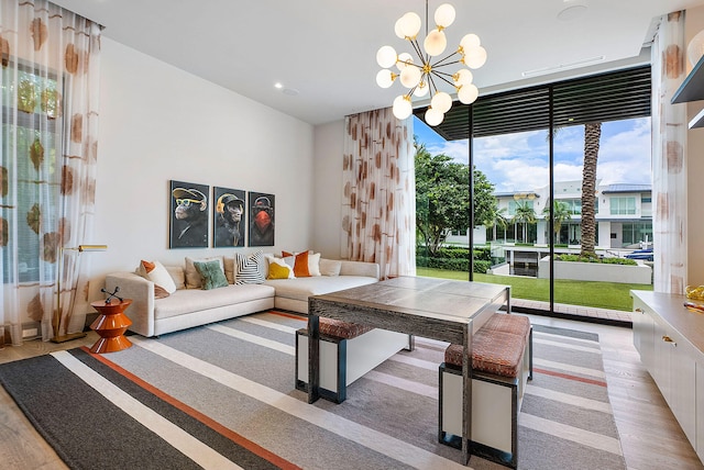 living room featuring a notable chandelier, light hardwood / wood-style floors, and a wall of windows