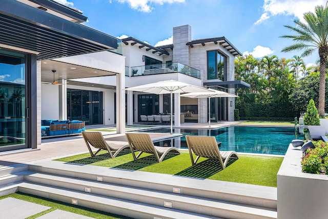 rear view of property featuring a balcony, an outdoor hangout area, a ceiling fan, an outdoor pool, and a patio area