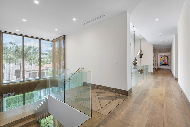 hallway featuring recessed lighting, visible vents, baseboards, an upstairs landing, and light wood-type flooring