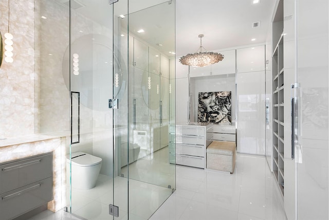 bathroom featuring tile patterned flooring, toilet, a shower with door, and tile walls