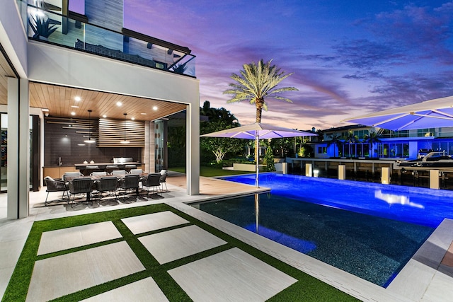 pool at dusk featuring outdoor lounge area, ceiling fan, and a patio