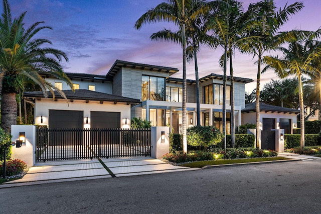 contemporary home featuring decorative driveway, fence, and stucco siding