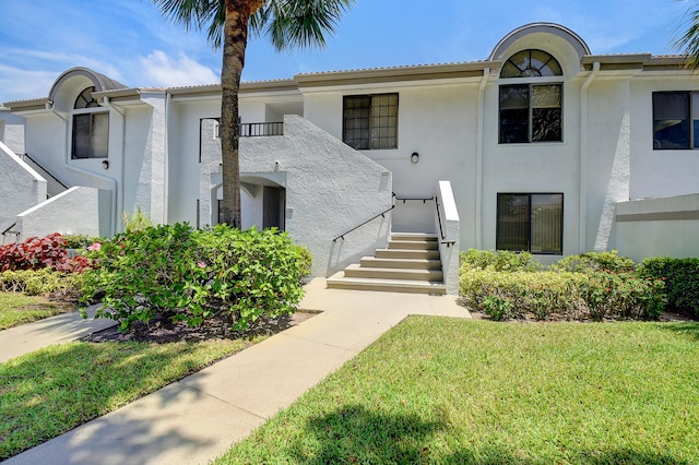 view of front of property featuring a front yard and a balcony