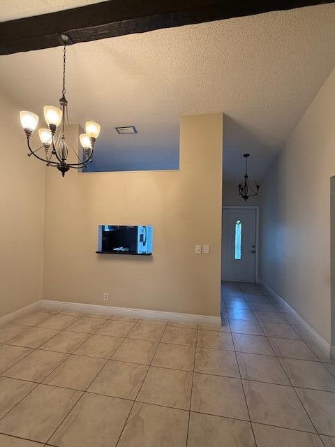 interior space featuring an inviting chandelier, a textured ceiling, light tile patterned floors, high vaulted ceiling, and beam ceiling