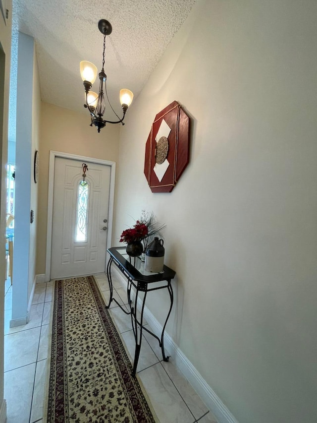 foyer featuring an inviting chandelier, a textured ceiling, and light tile patterned floors