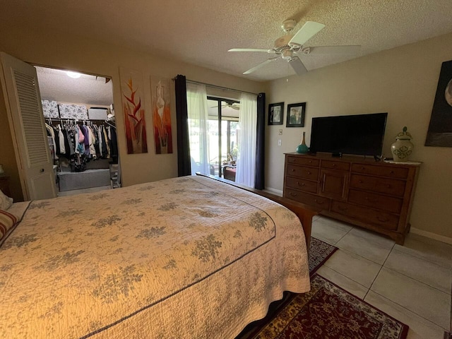 tiled bedroom with a closet, a spacious closet, a textured ceiling, access to exterior, and ceiling fan