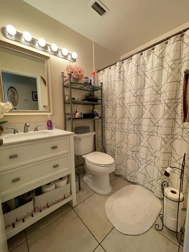 bathroom with toilet, vanity, tile patterned flooring, and walk in shower