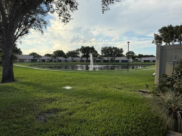 view of property's community with a lawn and a water view