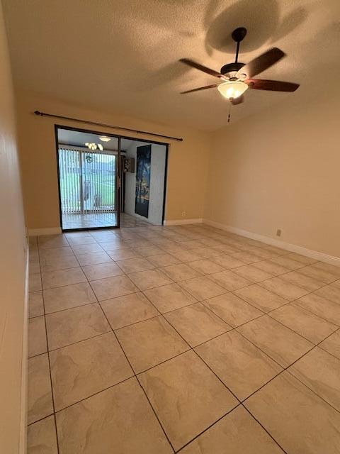 empty room with ceiling fan, a textured ceiling, and light tile patterned floors