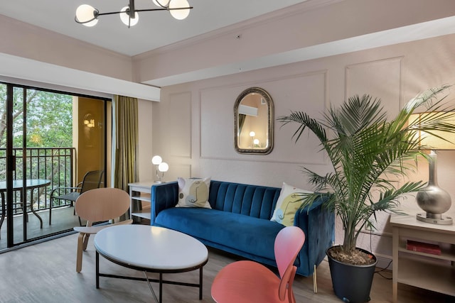 living area with crown molding, a chandelier, wood finished floors, and a decorative wall