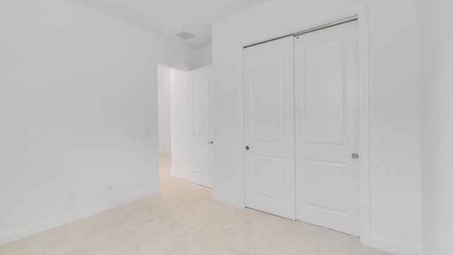 unfurnished bedroom with a closet and light colored carpet