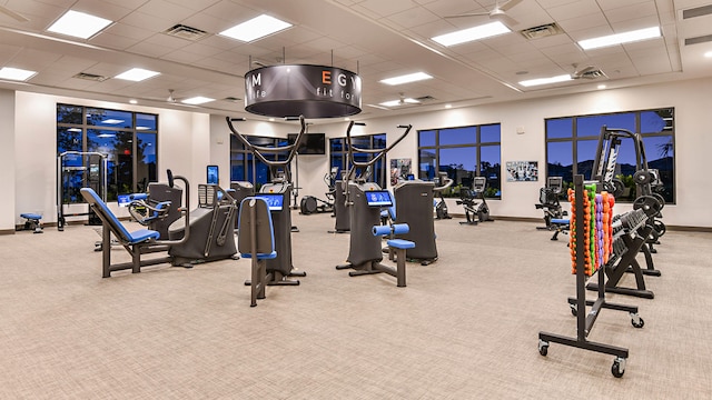 gym with a paneled ceiling and light colored carpet